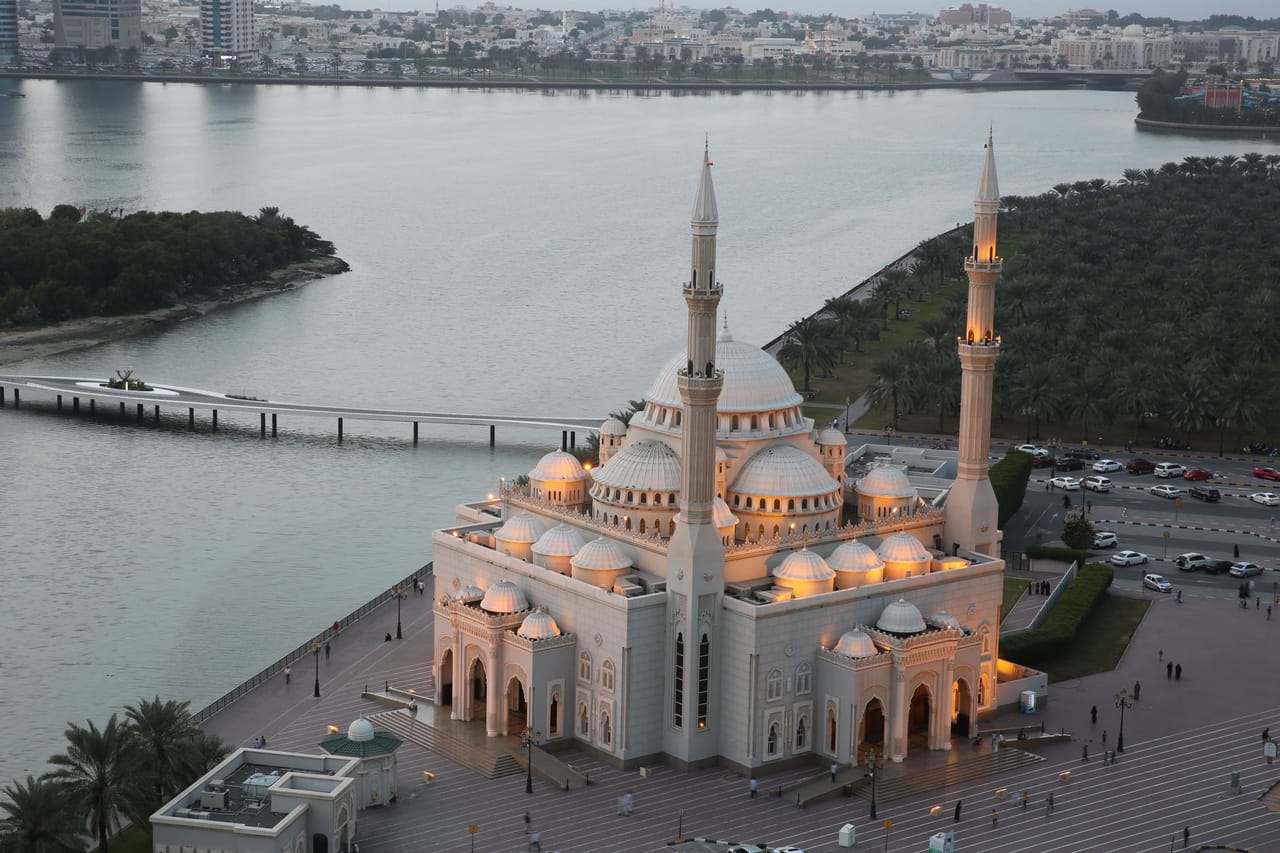 Мечеть Аль-Нур на набережной лагуны Халид в Шардже в сумерках, позади — мост на остров Аль-Нур