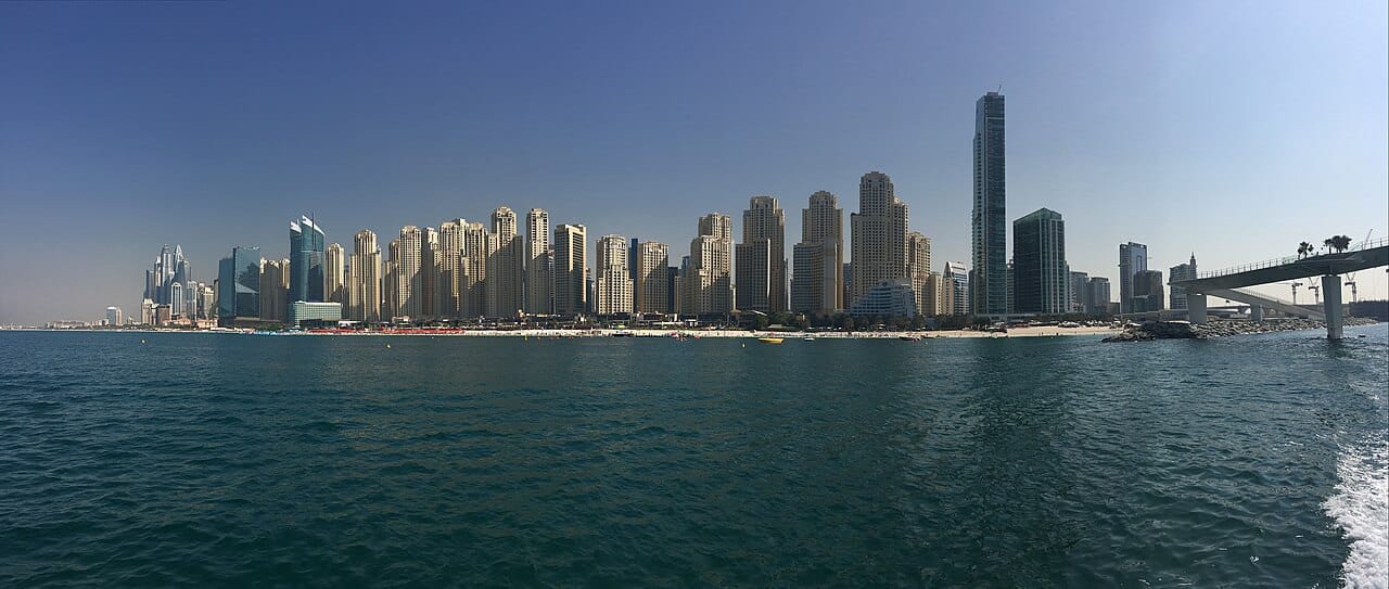 Пляж JBR и ряд башен Jumeirah Beach Residence с воды, за ними — силуэт Дубай Марины