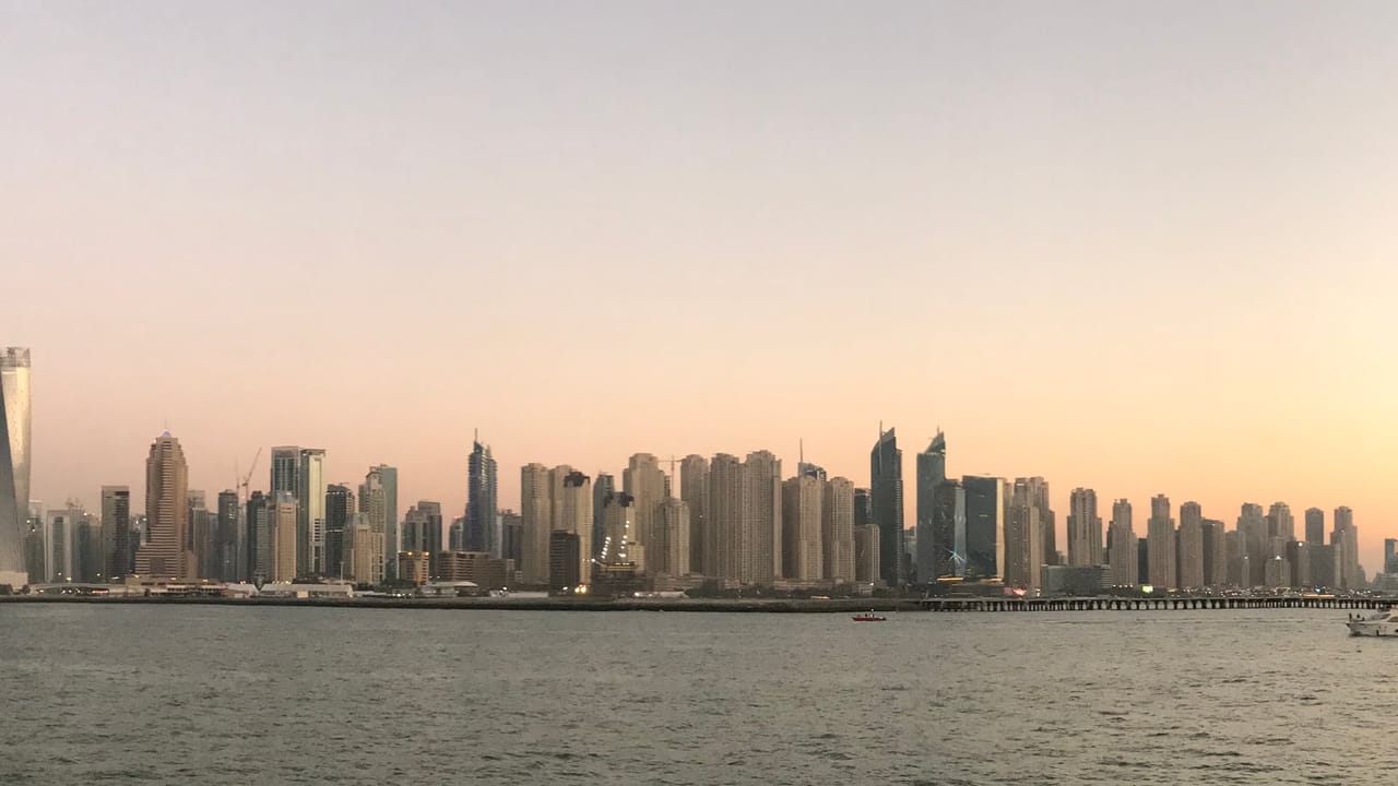 Небоскрёбы Дубай Марины и JBR на закате, вид через воду с Пальмы Джумейра