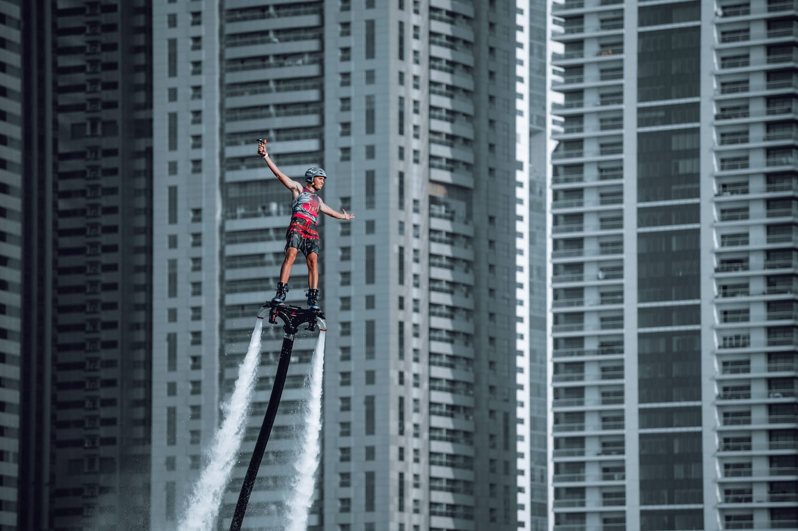Flyboarder steht über dem Wasser vor den Türmen der Dubai Marina