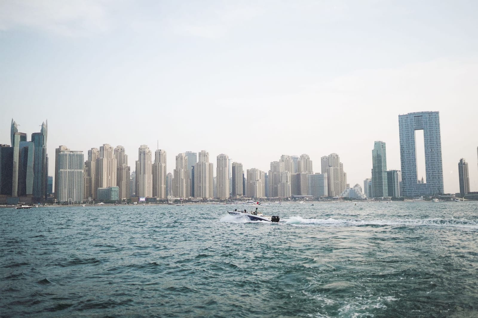 Speedboot fährt über das Wasser vor den Türmen der Dubai Marina