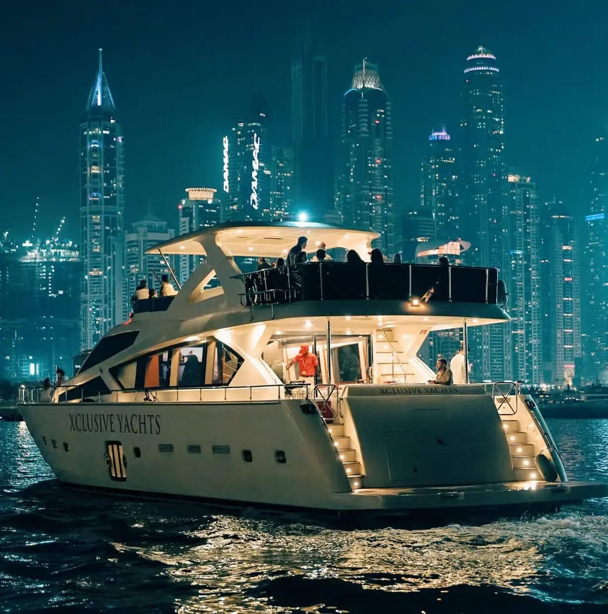 Party-Yacht vor der Skyline der Dubai Marina bei Nacht
