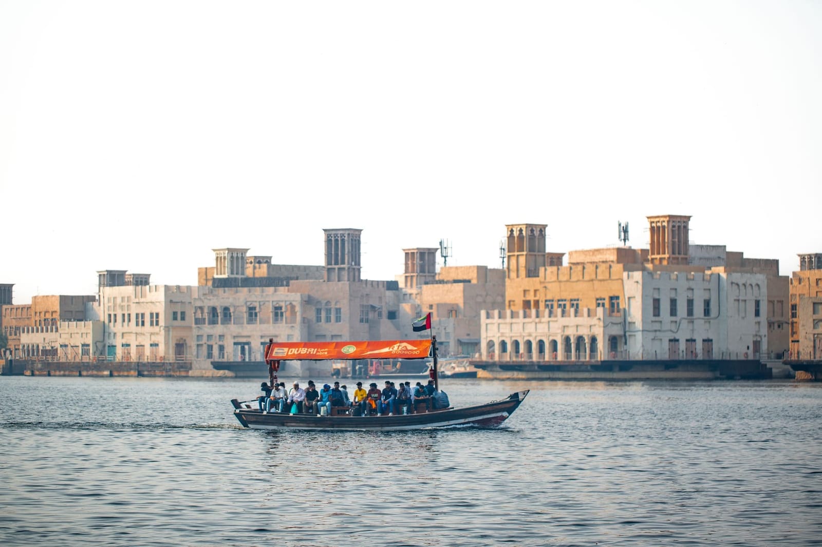 Eine Abra überquert den Dubai Creek vor den Windtürmen des alten Dubai